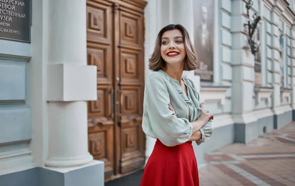 Una mujer con una falda roja se encuentra cerca de la puerta de un edificio histórico museo calles de la ciudad — Foto de Stock