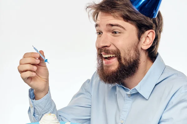 Un hombre con un plato de pastel y una camisa azul sobre un fondo claro fiesta de cumpleaños gorra corporativa — Foto de Stock