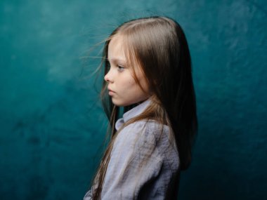 Turkuaz arka planda gri elbiseli bir kızın portresi gevşek saçlarının yakın plan çekimi.