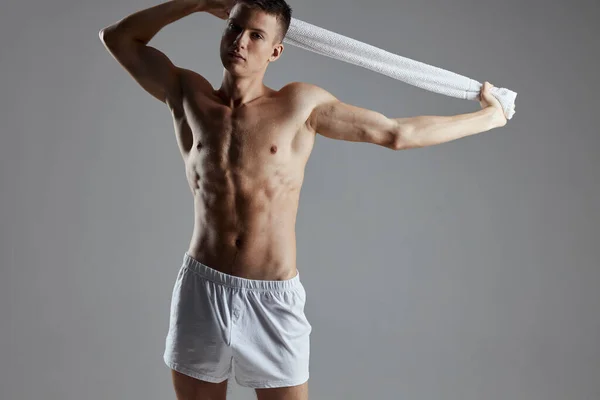 Cara com um tronco nu segurando uma toalha em suas mãos shorts brancos treino motivação isolado fundo — Fotografia de Stock
