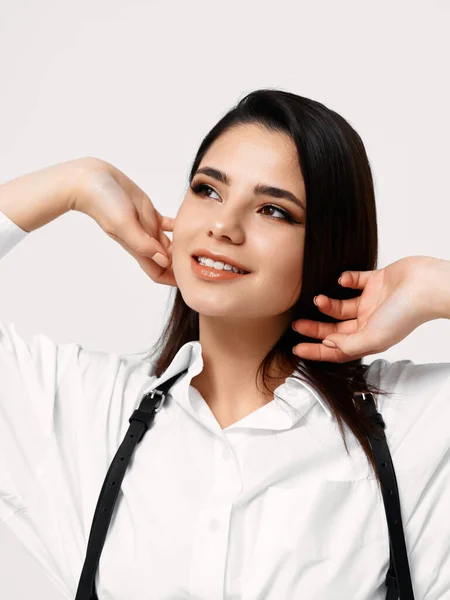 Femme aux cheveux foncés et en chemise blanche sur un fond clair sourire modèle — Photo