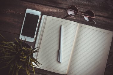 Kalem masası güneş gözlüğü telefon teknolojili defter.