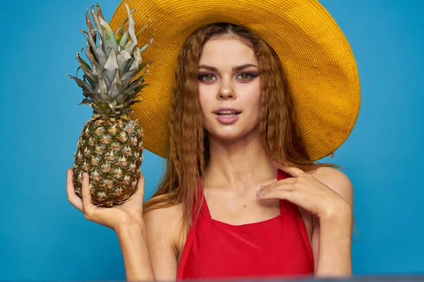 Glad söt kvinna i en hatt ananas i händerna Exotisk avkoppling blå bakgrund — Stockfoto