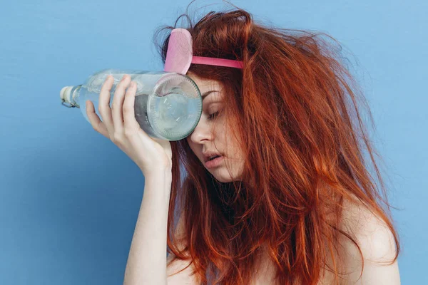 Mulher com máscara de sono ressaca garrafa de álcool nas mãos — Fotografia de Stock