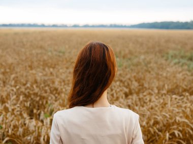 Kuru tarlaların yanında, kızıl saçlı bir kadın.