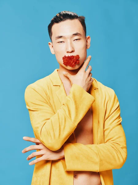 A man with a flower in his mouth on a blue background and a yellow jacket — Stock Photo, Image