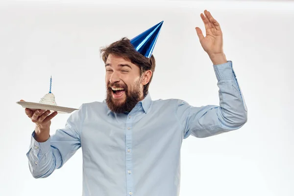 작은 배경에 케이크를 놓고 현란 한 모자를 쓰고 생일을 축하하는 남자 — 스톡 사진