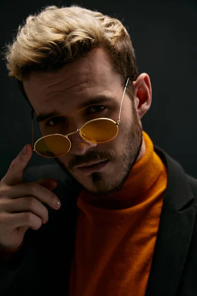 Blond man in bril op donkere achtergrond en oranje trui model — Stockfoto