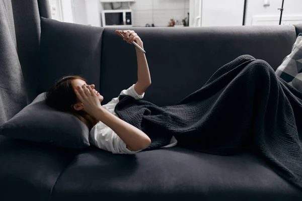 Mujer acostada en el sofá con un teléfono en sus manos sensor nueva tecnología almohada —  Fotos de Stock