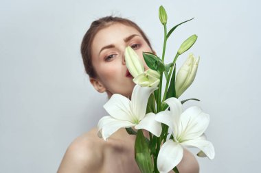 Gri arkaplan portresi üzerinde bir buket beyaz çiçekli bayan yakın çekimde kesilmiş.