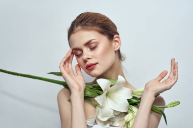 Gri arkaplan portresi üzerinde bir buket beyaz çiçekli bayan yakın çekimde kesilmiş.