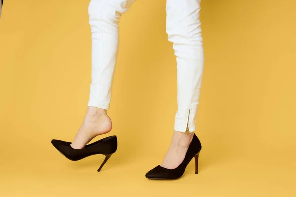 Mulher de sapatos pretos pernas cortadas iluminado fundo amarelo compras de moda — Fotografia de Stock