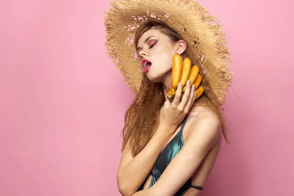 Kvinna i stranden halm hatt bananer håller frukt Exotisk baddräkt rosa bakgrund — Stockfoto