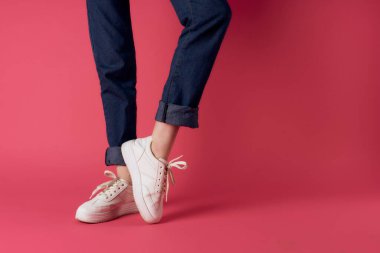 Kadın ayakları beyaz spor ayakkabılar sokak moda stüdyosu pembe arka plan