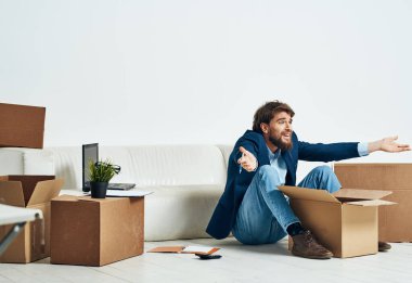 Bir adam, resmi bir işadamının duygularının açıldığı bir kutunun zemininde oturuyor.