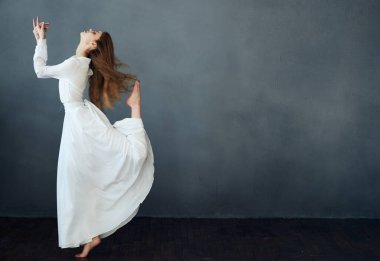 Gri arkaplan üzerinde beyaz elbiseli romantik kızıl saçlı kadın.