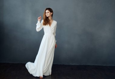 Gri arka planda beyaz elbiseli bir kadın dans mankeni.