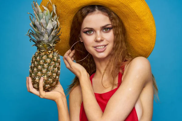 Kvinna i gul hatt med ananas i händerna känslor rolig livsstil sommar frukt blå bakgrund — Stockfoto