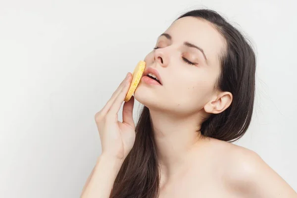 Mulher com ombros nus limpa o rosto com esponjas — Fotografia de Stock