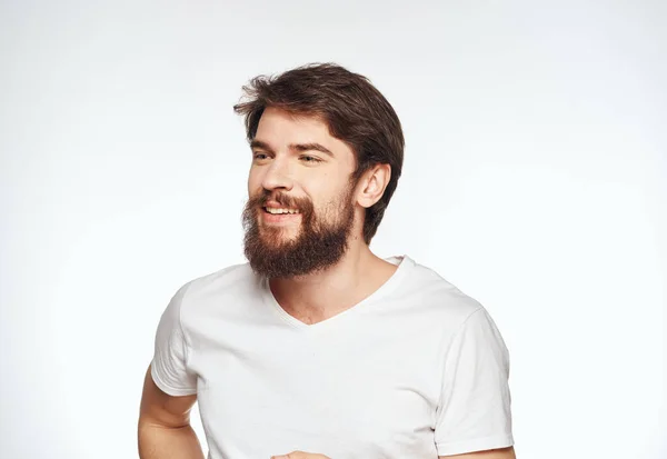 Retrato de un hombre enérgico con una camiseta blanca sobre un fondo claro recortado —  Fotos de Stock