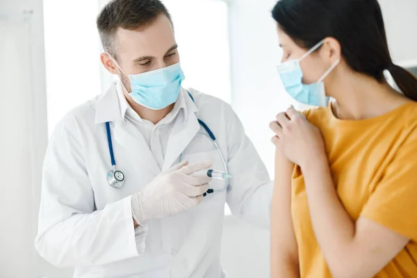 의사는 노란색 티셔츠를 입고 백신 접종을 위해 손에 주사기를 쥐고 있다 — 스톡 사진