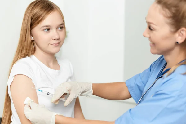 Kvinnlig läkare ger en injektion till en flicka i handen på ett sjukhus hälsa covid — Stockfoto