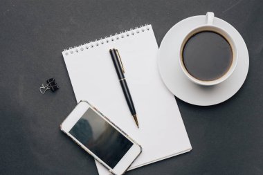 Kalem bardağı telefon teknolojisiyle birlikte çalışma masası not defteri.