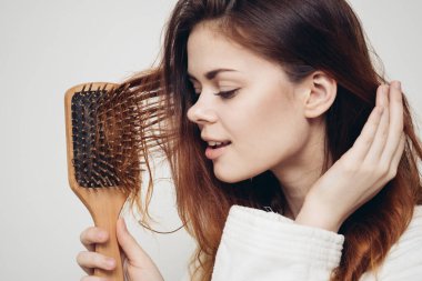 Taraklı, sağlıklı saçlı, açık renk beyaz cüppeli model bir kadın.