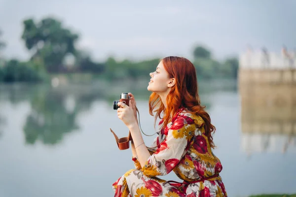 Frau in buntem Kleid mit Kamera in der Hand im Freien — Stockfoto