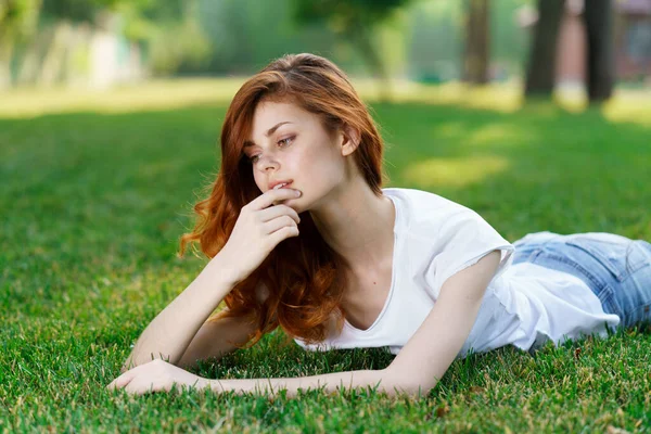 Frau liegt auf dem Rasen im Park und hat Handy in der Hand — Stockfoto