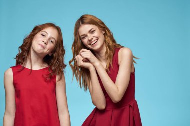 Aile annesi ve kızı sarılır kırmızı elbiseler iletişim duyguları mavi arka plan