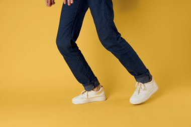 Ayak jesti beyaz spor ayakkabı moda kot pantolon sokak tarzı sarı arka plan