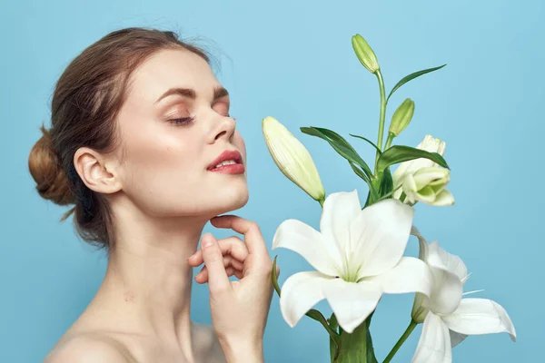 Hermosa chica con un ramo de flores blancas sobre un fondo azul vista recortada hombros desnudos retrato — Foto de Stock