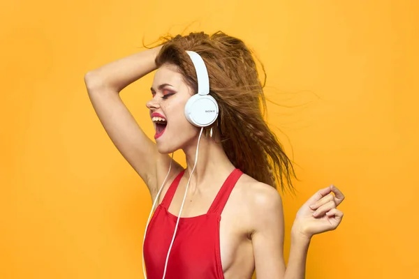 Женщина в наушниках слушает музыку красная футболка эмоции моды желтый фон образ жизни — стоковое фото
