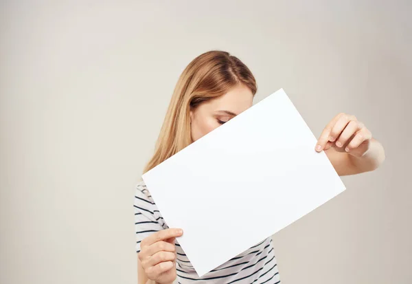 Blondine vrouw met een wit vel papier in de handen van een reclamebanner — Stockfoto