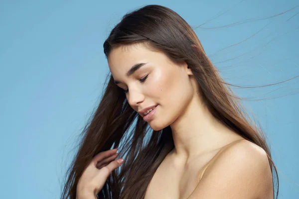 Hübsche Brünette nackte Schultern lange Haare Hautpflege blauer Hintergrund — Stockfoto