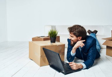 Bir adam dizüstü bilgisayar kutularının önünde bavullarını boşaltan profesyonel bir işadamıyla yatıyor.