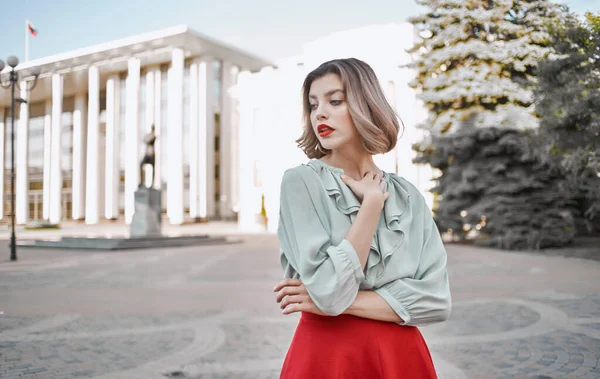 A woman in a shirt skirt strolls through the central streets of the city and tall buildings in the background — Stock Photo, Image