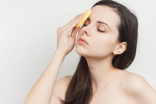 Mujer con hombros desnudos se limpia la cara con esponjas —  Fotos de Stock