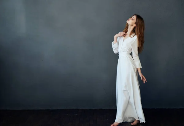Bonita mulher branco vestido estúdio realizando dança cinza fundo modelo — Fotografia de Stock