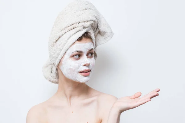 Naken kvinna med vit grädde i ansiktet och en handduk på huvudet — Stockfoto