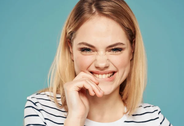 Cheerful blonde woman smiling on blue background grimacing model laughing — ストック写真