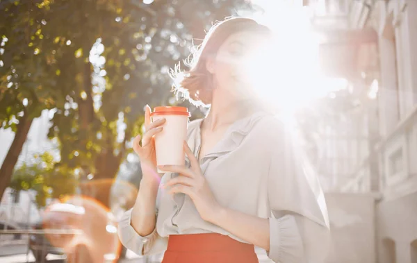 Женщина с чашкой кофе в руке возле кирпичного здания и летом макияж красная юбка — стоковое фото