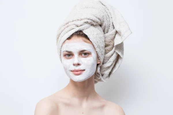 Woman with a towel on her head and a moisturizer on her face — Stock Photo, Image