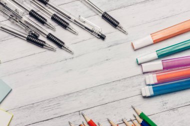 İşaretler, tahta bir masaya kalemler ve renkli kağıt ofis kağıtları.