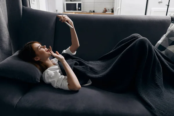 Kobieta leżąca na kanapie z telefonem w ręku widok z boku wewnętrzny komfort przycięty widok — Zdjęcie stockowe