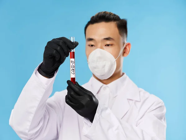 A man of Asian appearance in a protective mask blood test black gloves diagnostics