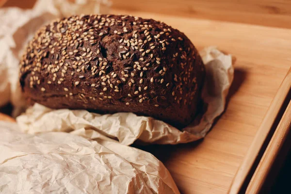 Bir somun ekmek unu, ahşap tahta tepsi ve kağıt ambalaj. — Stok fotoğraf