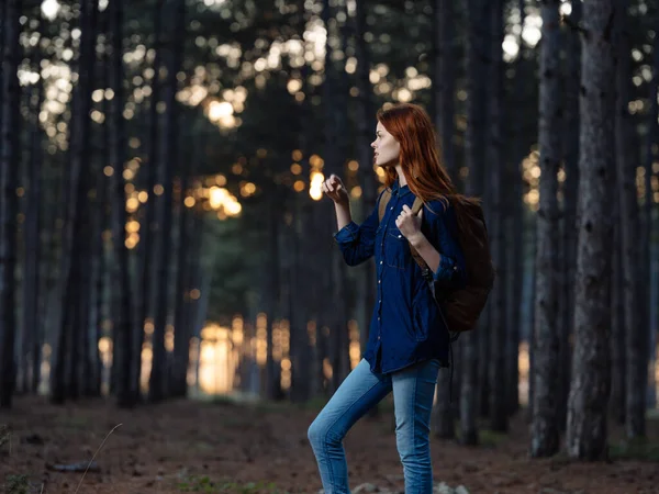 Ευτυχισμένη κοκκινομάλλα γυναίκα με μπλε πουκάμισο ταξιδεύει σε ένα πευκοδάσος στη φύση — Φωτογραφία Αρχείου