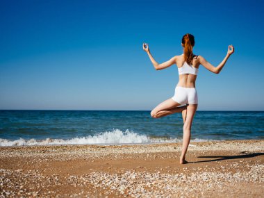 Plajda beyaz mayo giyen bir kadın tropik bir tatil yapıyor.